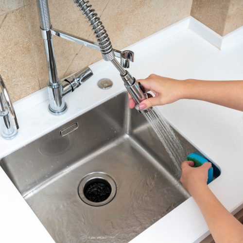 A,Person,Using,A,Flexible,Faucet,Sprayer,And,A,Blue